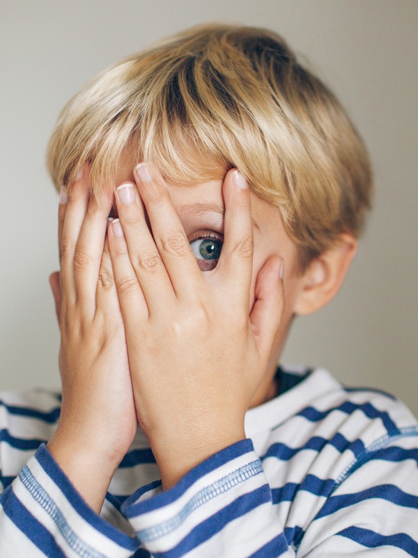 Little Scared Girl Closing Face With Hands and Peeking Through