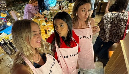 Three women in aprons collaborating in a lively restaurant, showcasing teamwork and culinary passion.